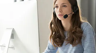 Applied Epic for Salesforce A woman with a headset on while using her computer