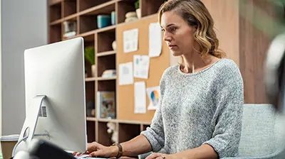 Indio  A woman wearing a gray sweater, sitting in an office while using a computer