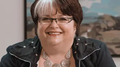 Western Financial Group Woman smiling with large painting hanging on the wall of her office in the background.