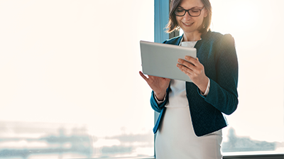 Applied Performance Management: Book of Business A young businesswoman working on her tablet in front of a window