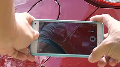 Applied MobileInsured: Virtual Assistant for Claims Management Two hands holding a phone while taking a picture of a red car