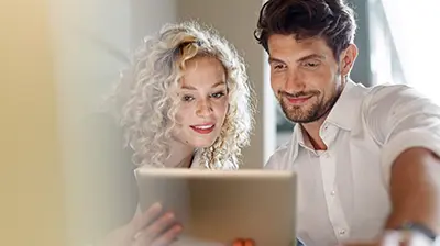Product Release Hub Woman and man dressed in casual attire smiling at tablet screen they are holding.
