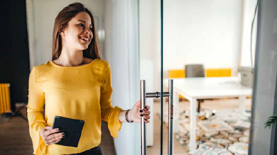 Opening Up Innovation A woman in a yellow blouse, holding a tablet while opening a glass door