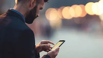 A man slightly facing away from the camera while using his smart phone