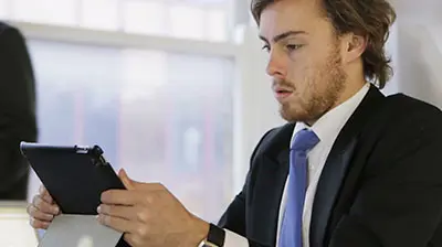 Applied IVANS Exchange Promo Man in business attire using a smart tablet