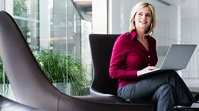 Applied Analytics A woman sitting in a chair while using a laptop that is resting on her crossed legs