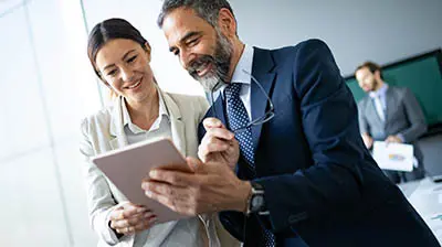 Surpassing Customer Expectations and Enhancing Business Operations To colleagues sharing a smart tablet while smiling