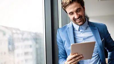 Making Informed Decisions with Data You Already Have A man standing next to a window while smiling down at a tablet in his hand