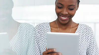 Applied Marketing Automation A woman in a black and white blouse, smiling while holding a tablet